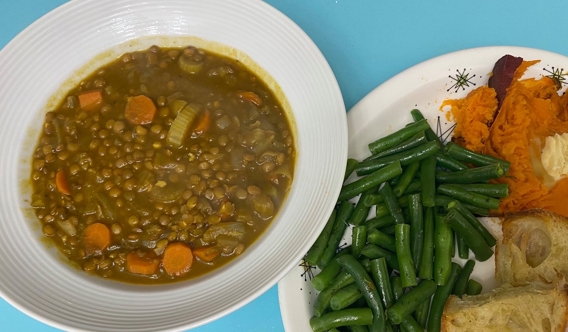 Pumpkin Curry Lentil soup in bowl with side of green beans, yams, and bread